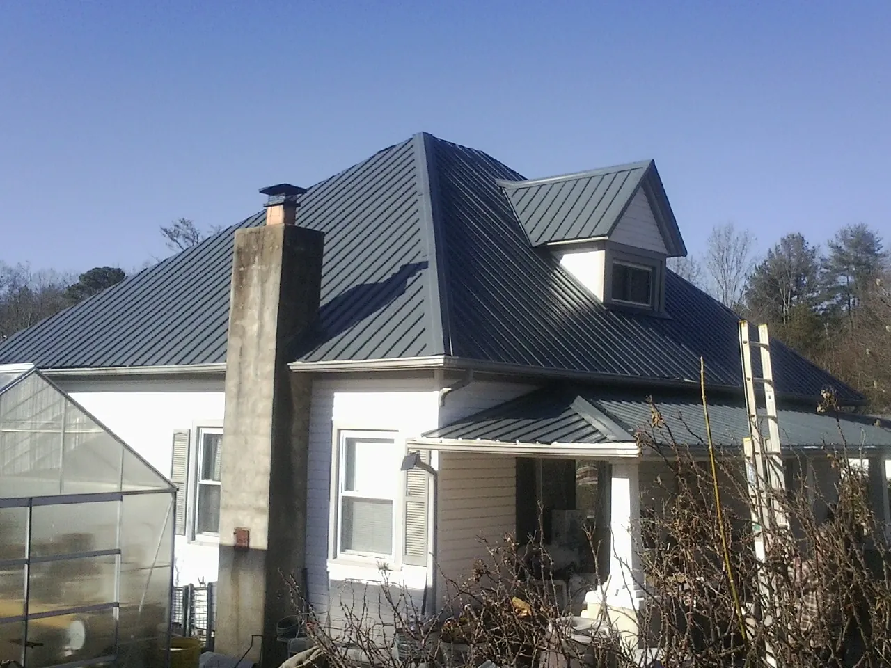 Dark blue standing seam metal roof on a white farmhouse with dormer — Slate & Tile Roof Repair by Roofing Brothers in Walnut Cove