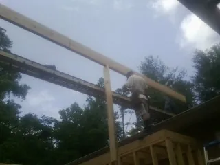 Carpenter setting a ridge beam over a new addition frame — Ice Dam Removal by Roofing Brothers in Walnut Cove
