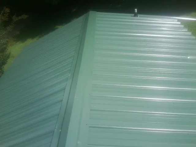 New green metal panels meeting at the ridge of a roof — Flat Roof Repair work by our crew in Walnut Cove
