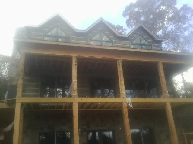 Dormers and porch framing on a large log home under construction — Roof Coating work by our crew in Walnut Cove