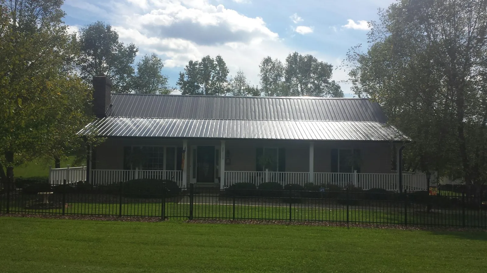 Gray metal roof on a brick ranch with a full width front porch — Gutter Guard Installation work by our crew in Walnut Cove