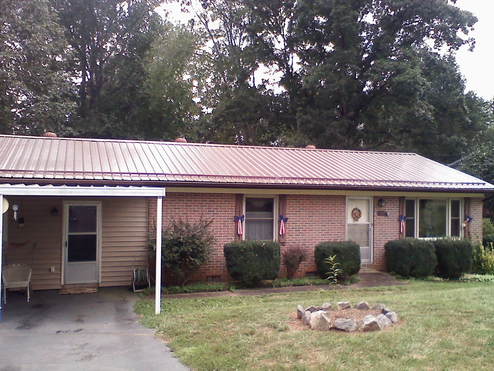 Bronze metal roof and carport on a brick ranch home — Roof Repair work by our crew in Walnut Cove